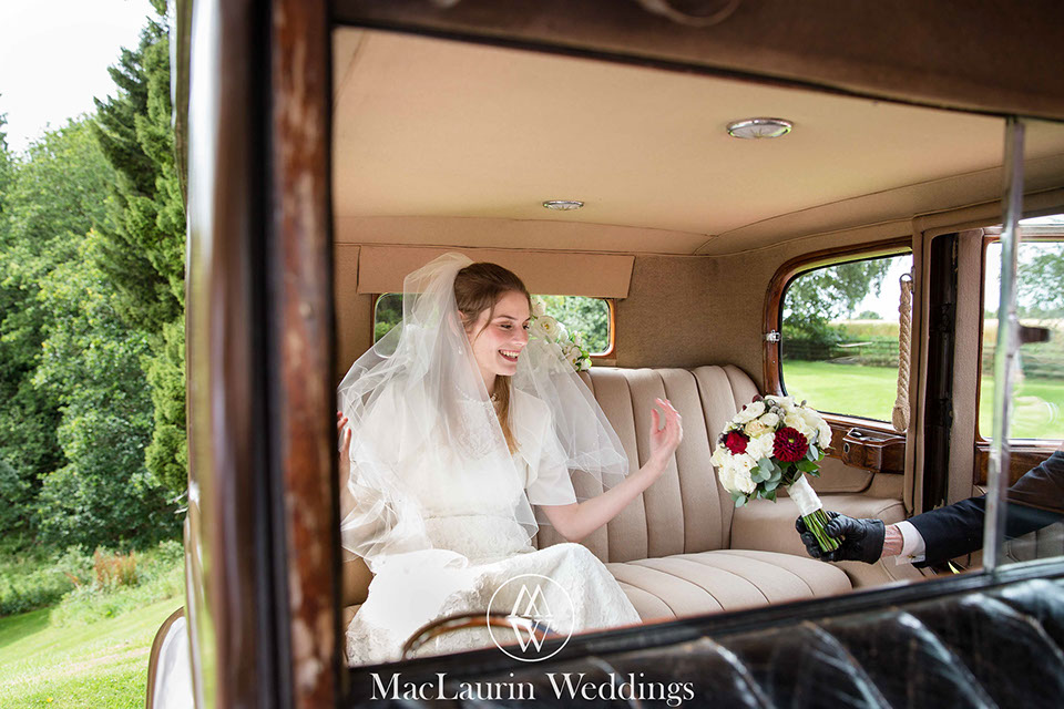 a bride in wedding car with bouquet a happy bride in the wedding car recieving her bouquet from the chauffeur