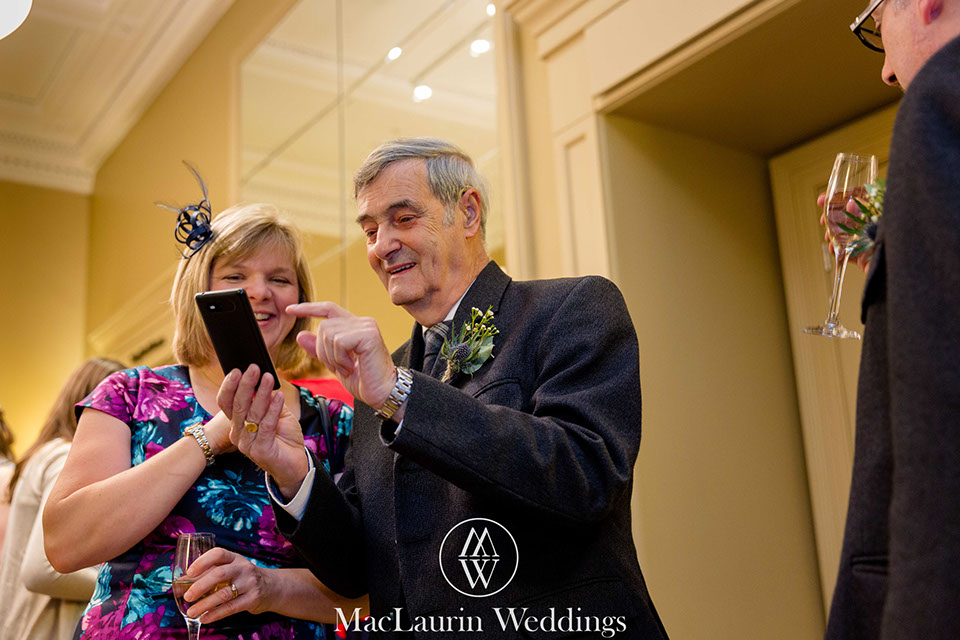 drinks reception at the rivers suite napier university  guests enjoying some images on a smartphone during the the drinks reception at the rivers suite napier university